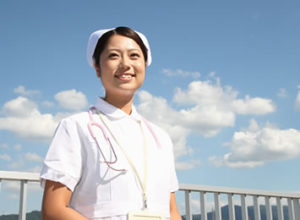 スタッフ採用情報/青空に雲の背景屋上にて女性看護師さんのすがすがしい笑顔